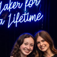 Two girls anchor up in front of Laker for a Lifetime neon sign.